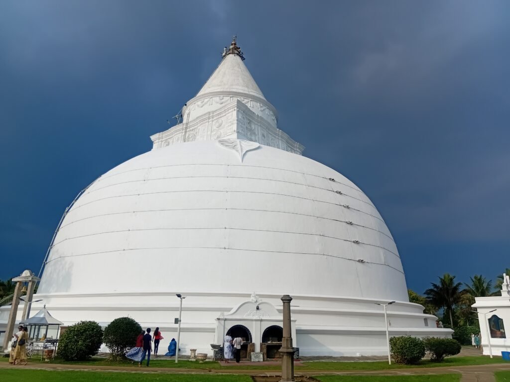 White Buddhist stupa in Tissamaharama under a dark tropical sky