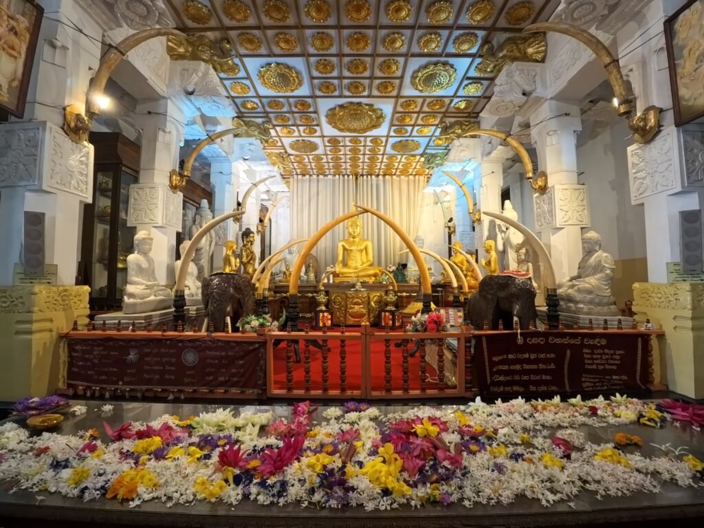 Inside the Temple of the Sacred Tooth Relic, Kandy. Golden Buddha shrine with elephant tusks and flower offerings at the Temple of the Sacred Tooth Relic in Kandy